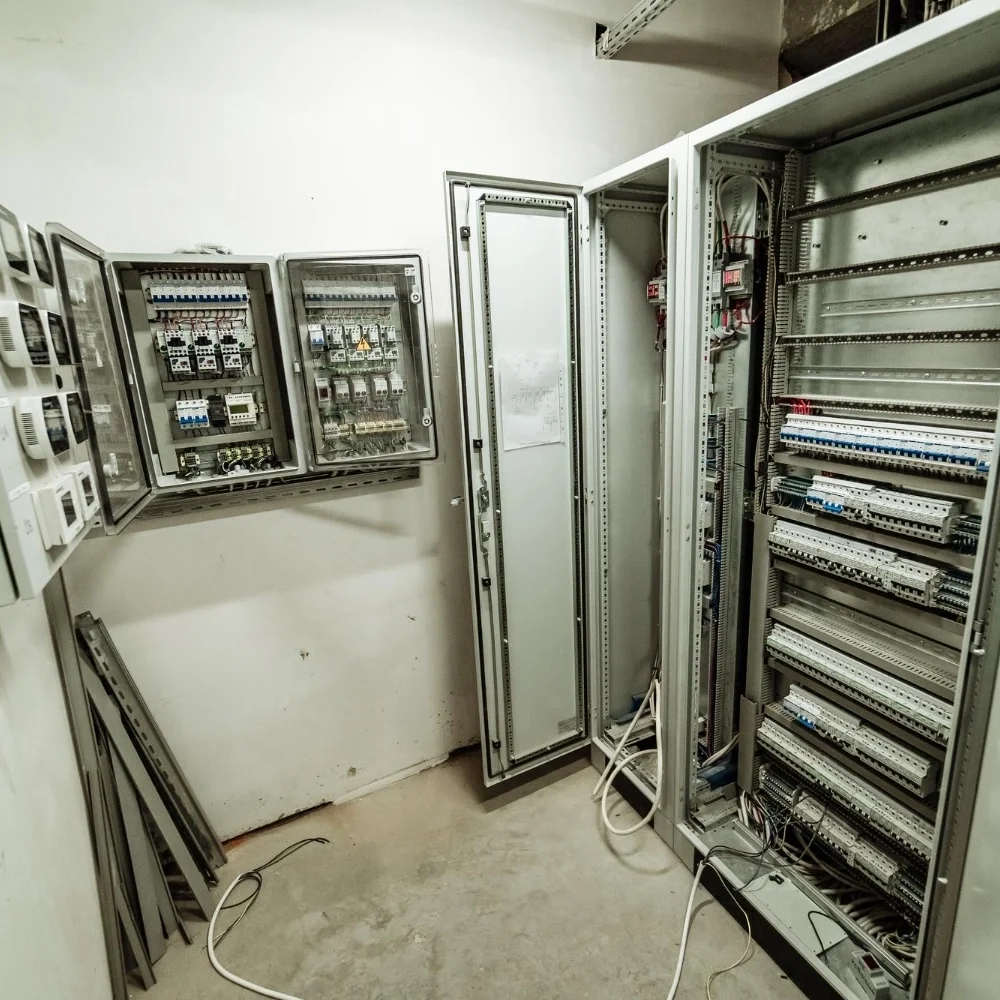 Industrial electrical distribution panels with open cabinets showing circuit breakers and wiring - About - E-Abel - E-Abel - About - E-Abel - E-Abel Panneaux de distribution électrique industriels avec armoires ouvertes montrant les disjoncteurs et le câblage