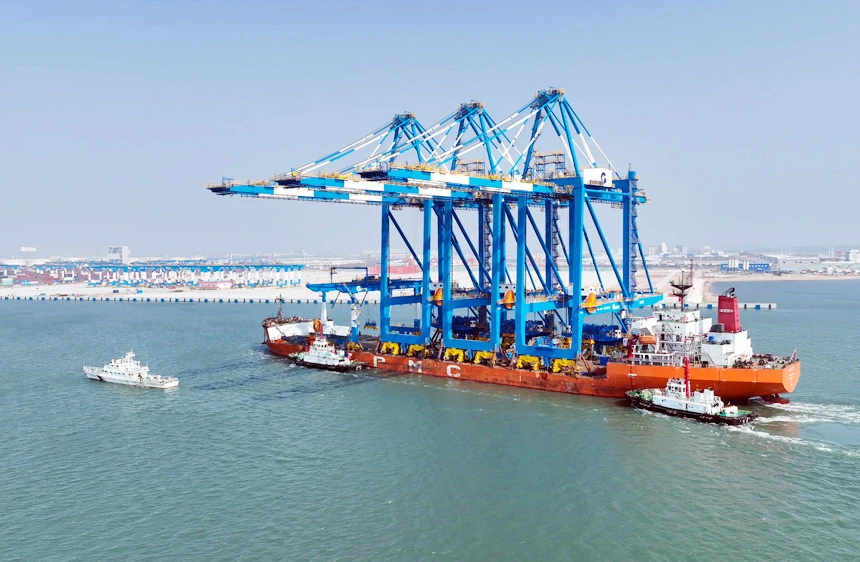Large cargo ship transporting blue gantry cranes at sea - Netherlands: Powering the Next Generation of Automated Ports - E-Abel - E-Abel - Knowledge Hub - E-Abel - E-Abel Grand cargo transportant des portiques bleus en mer