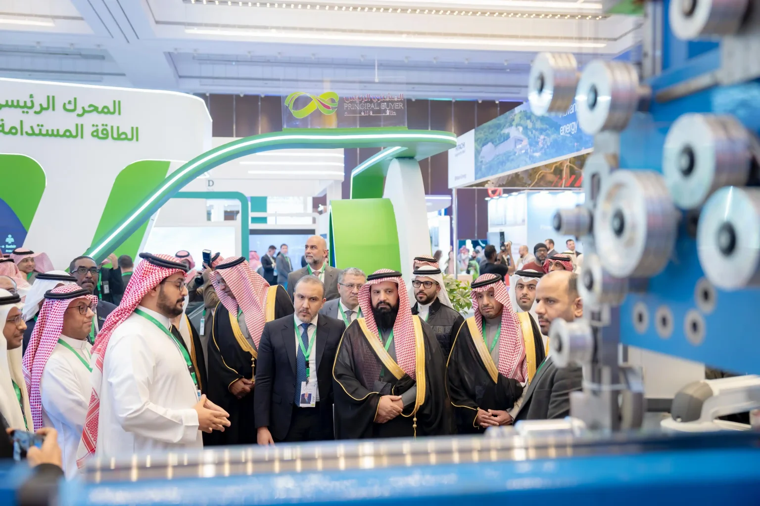 Officials visiting a sustainable energy exhibition booth - Saudi Arabia: Power Security for Large-Scale Events - E-Abel - E-Abel - Knowledge Hub - E-Abel - E-Abel Des officiels visitent un stand d'exposition sur les énergies durables.