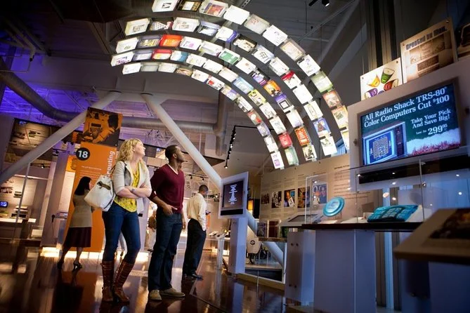 People exploring a tech museum exhibit with colorful digital displays - Europe Historic Museum Upgrade: Custom Power & Monitoring System - E-Abel - E-Abel - Knowledge Hub - E-Abel - E-Abel Des visiteurs explorent une exposition d'un musée des technologies avec des écrans numériques colorés.